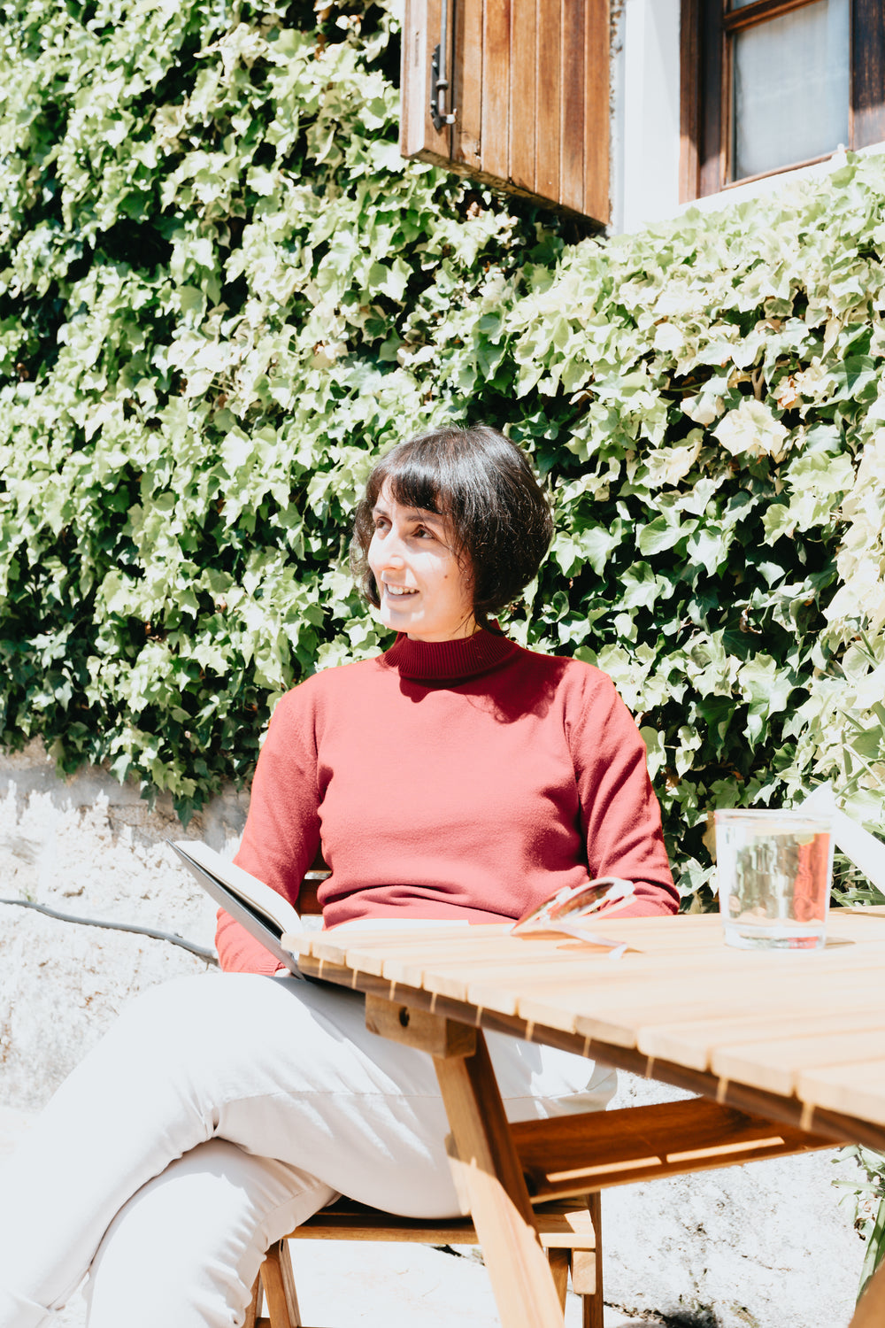 woman sits at a wooden table and holds a book