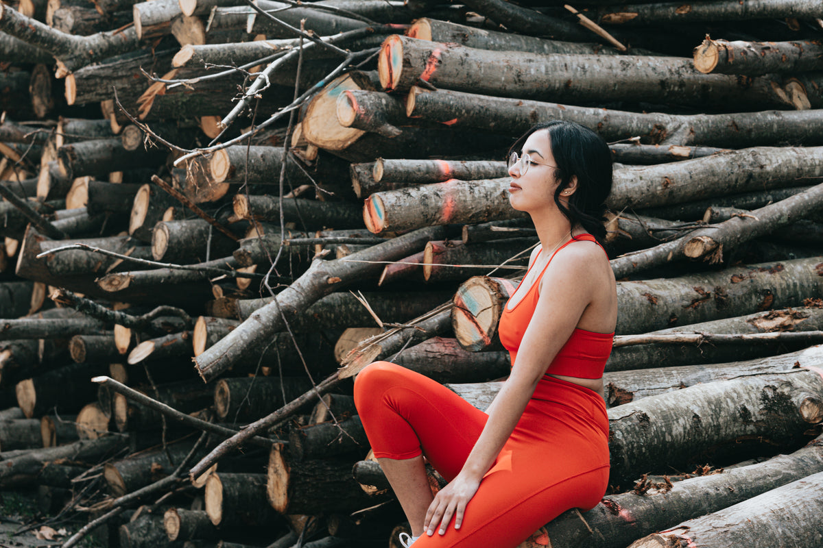 woman sits by large wooden branches