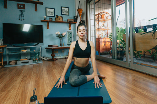 woman sits in a yoga pose in their living room