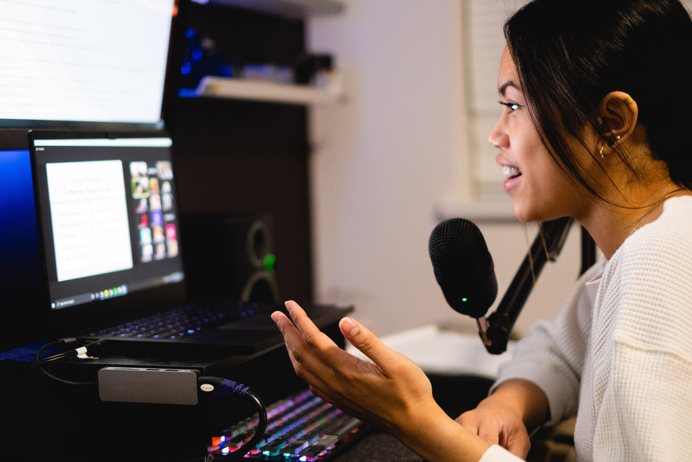 woman sits in front of a computer and talks into a microphone