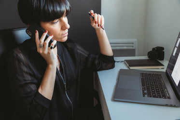 woman sits in front of computer talking on the phone