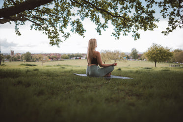 woman sits in self reflection under a tree