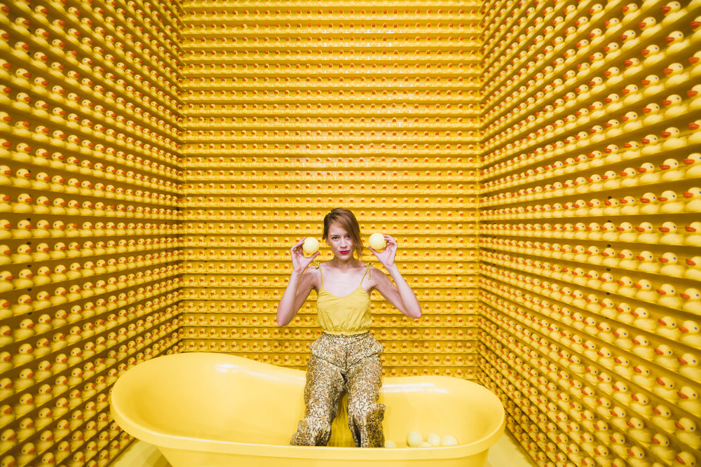 woman sits in tub with rubber duckies