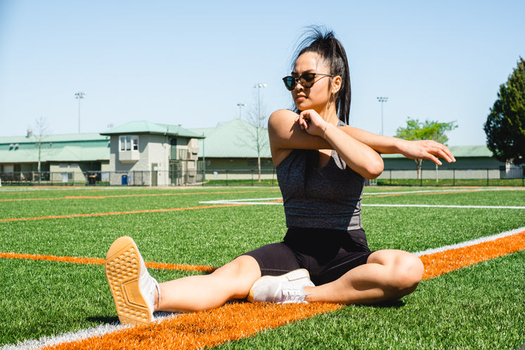 Woman Sits On A Sports Fields And Stretches Her Arms