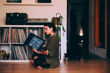 woman sits on floor looking at records