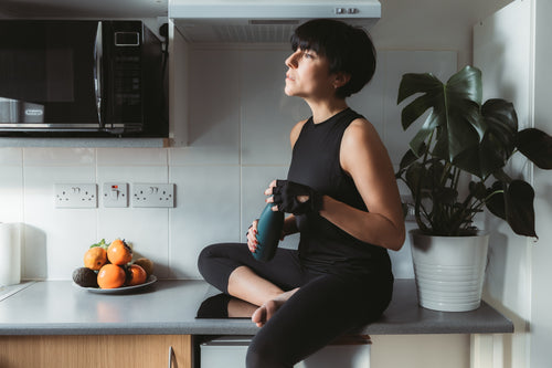 woman sits on kitchen counter in workout attire