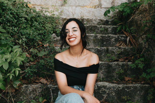 woman sits on stone steps and smiles towards the camera