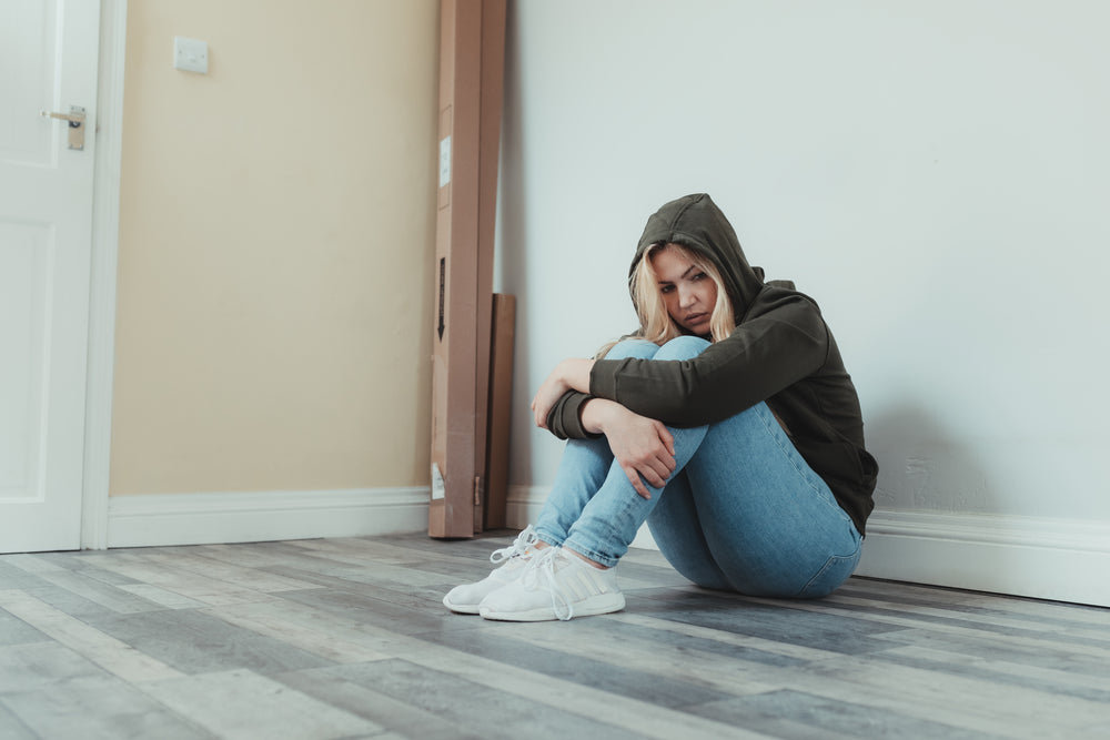 woman sits on the floor and holds her legs