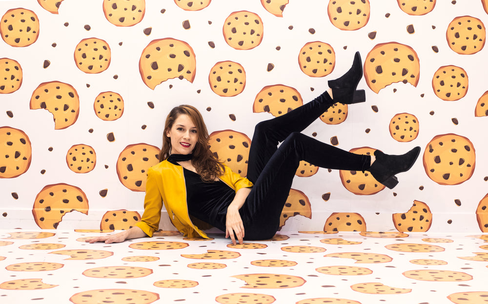 woman sits on the floor of a room covered cookie wallpaper