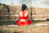 woman sits outdoors on a pink yoga mat