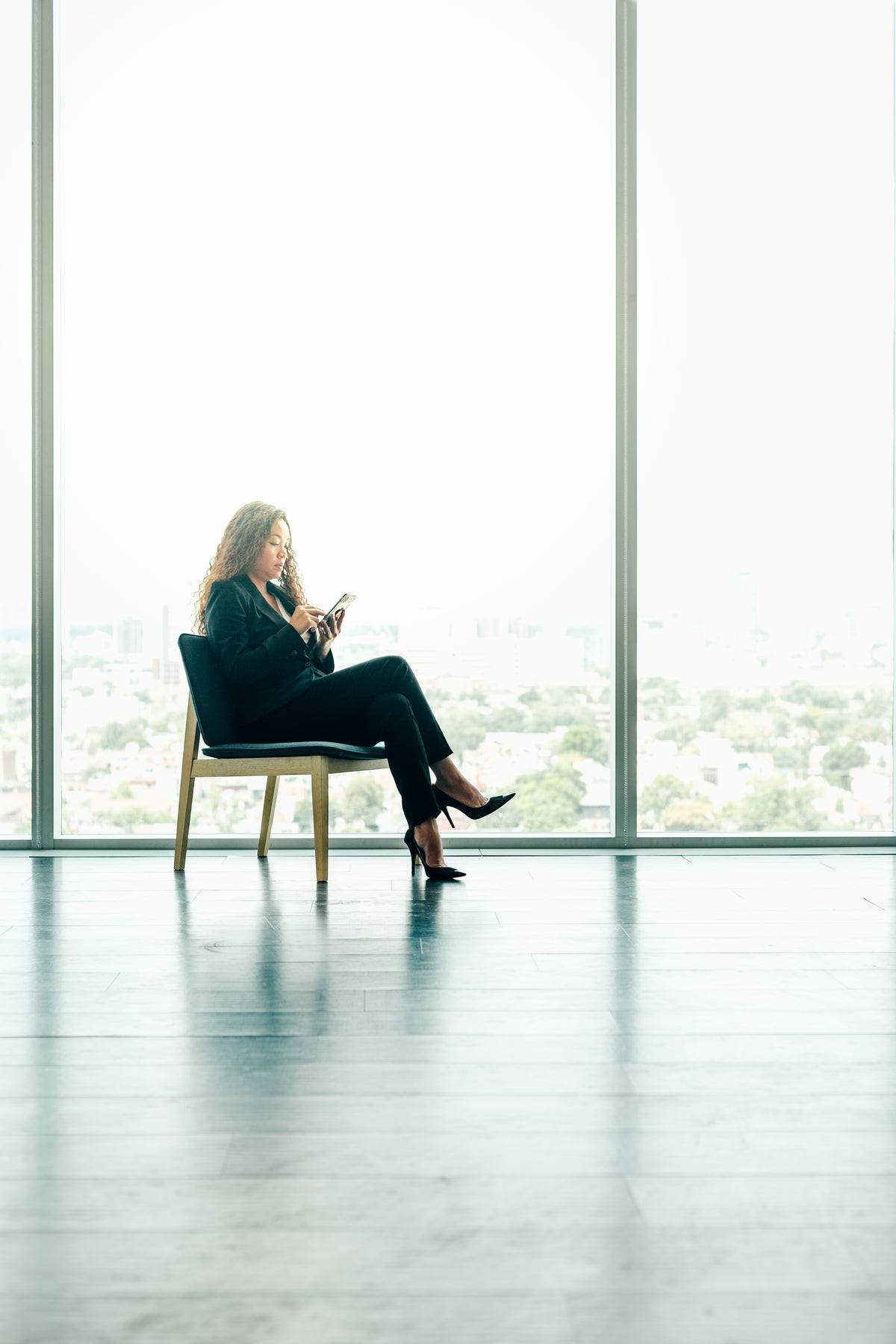 女人坐在现代办公室窗户旁打电话