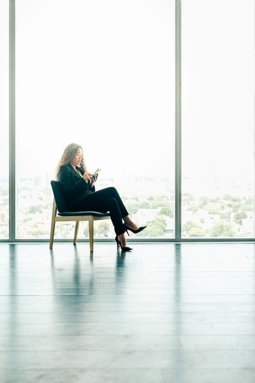 woman sitting on phone by modern office windows
