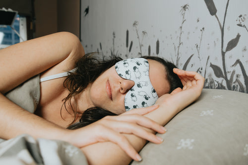 woman sleeps with a facemask with sheep on it