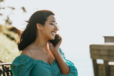 woman smiles and holds a cellphone to her ear