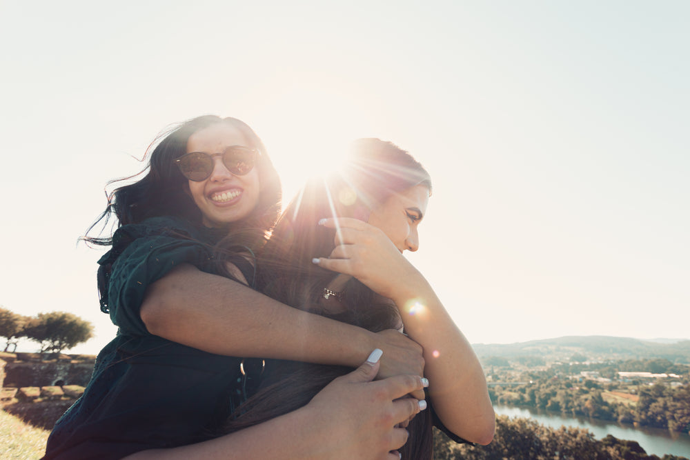 woman smiles and hugs a woman from behind