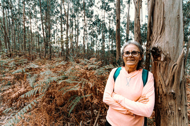 woman smiles and leans on a large tree