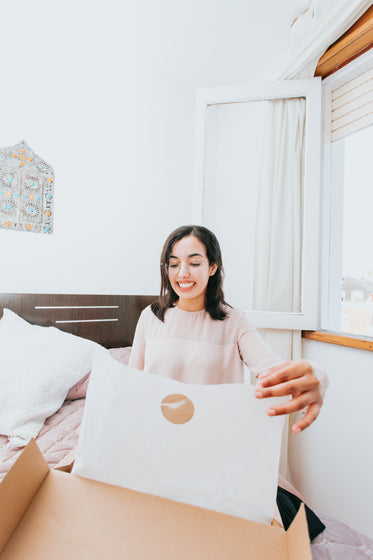 woman smiles and opens a box with white tissue paper