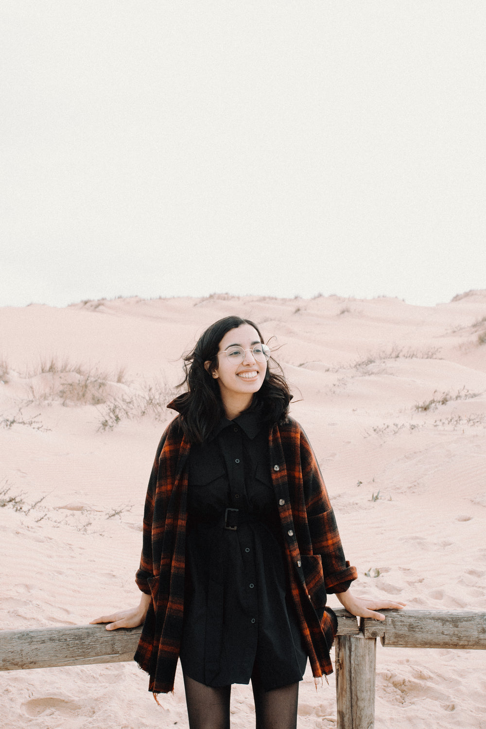 woman smiles and stands in front of sandy hills