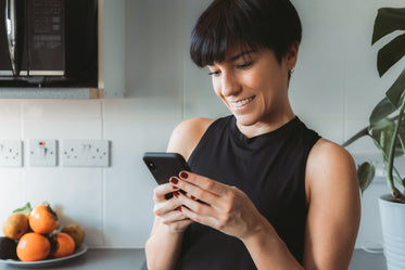 woman smiles as she looks at her cellphone