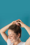 woman smiles as she puts her hair up in a sparkly scrunchie