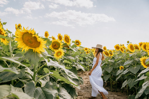 woman smiles as she stands in a sunflower field