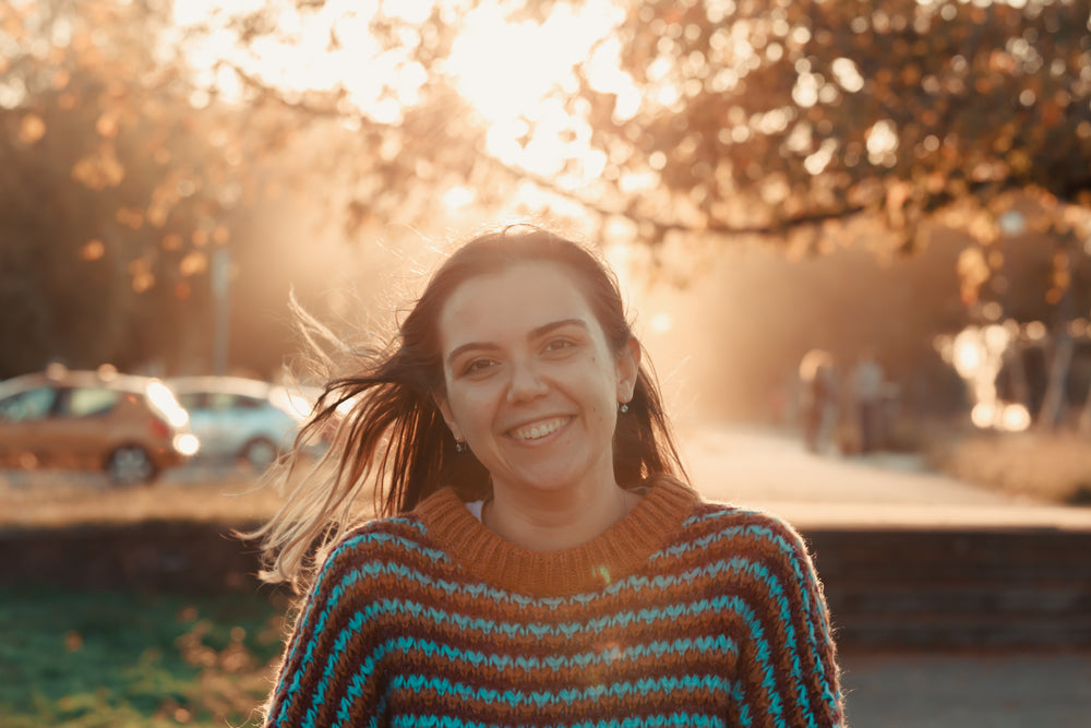 woman smiles at golden hour into a camera