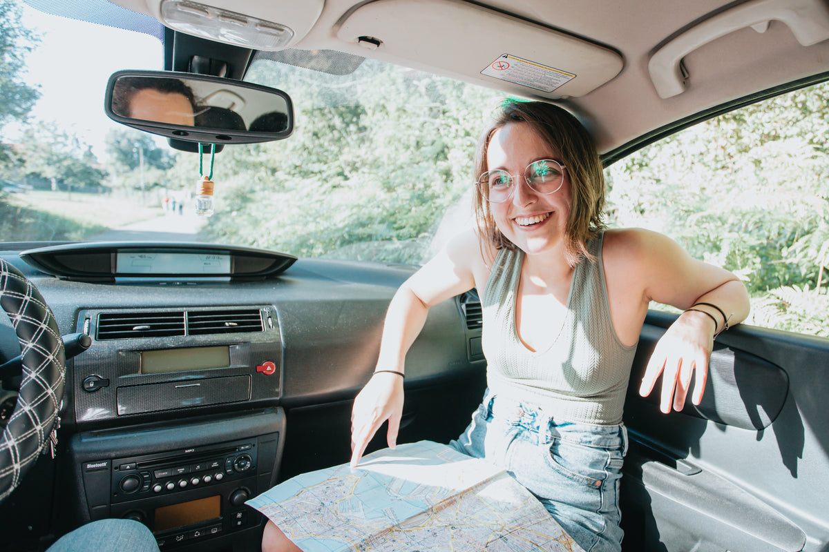 女人在车里微笑，腿上放着地图