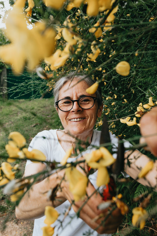 woman smiles through branches of a flowering tree