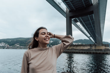 woman smiles wide standing under a large bridge