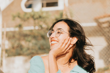 woman smiling and holding her head up with one hand