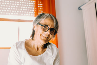 woman smiling to the camera with orange curtains behind