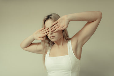 woman stands and covers her eyes with her palms outwards