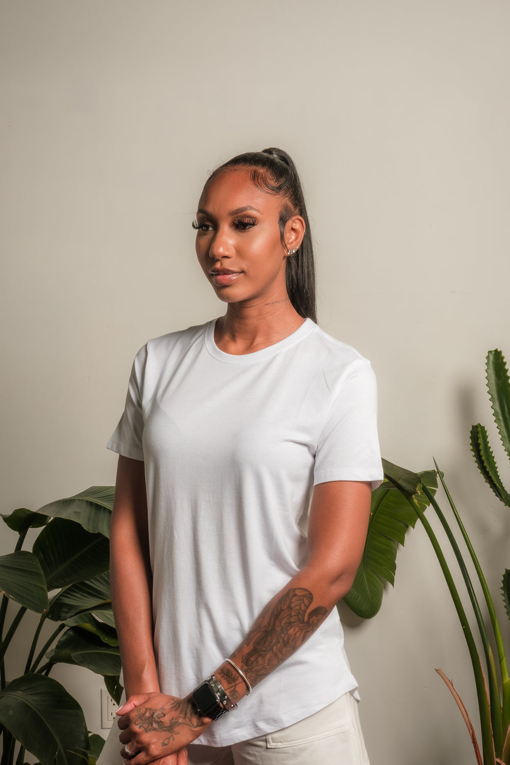 woman stands by house plants and clasps hands in front of her