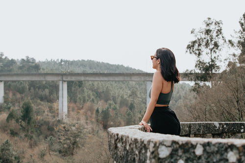 woman stands in at stone lookout and take in the forest view