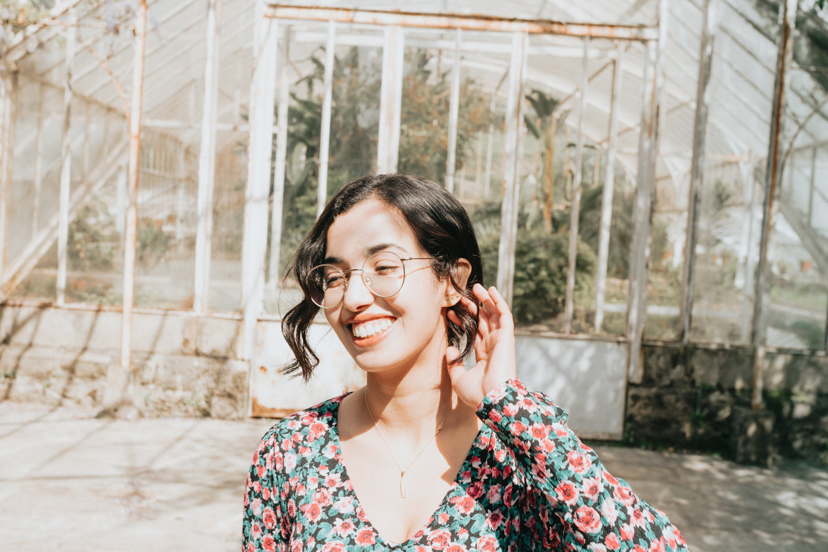 woman stands in front of a green house and smiles