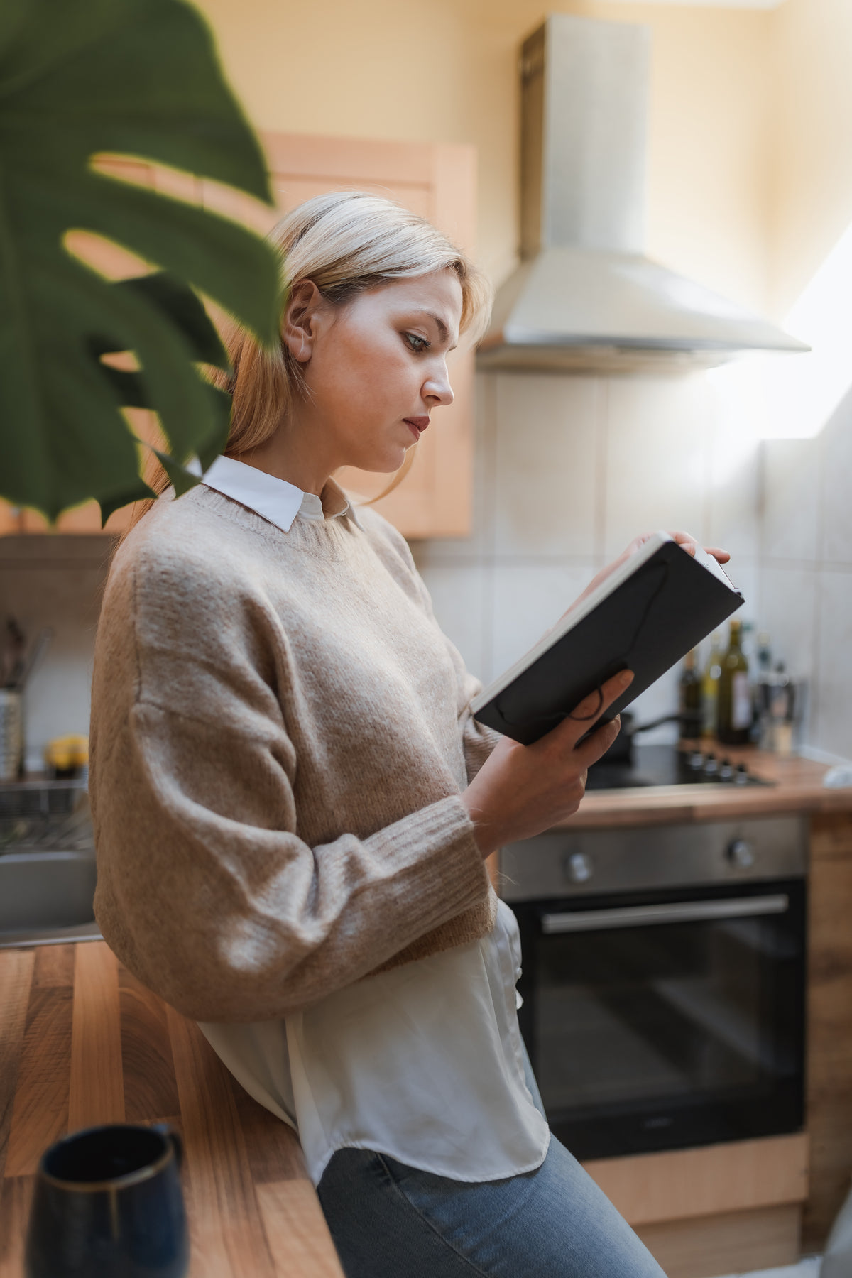 woman stands in her kitchen reading a book