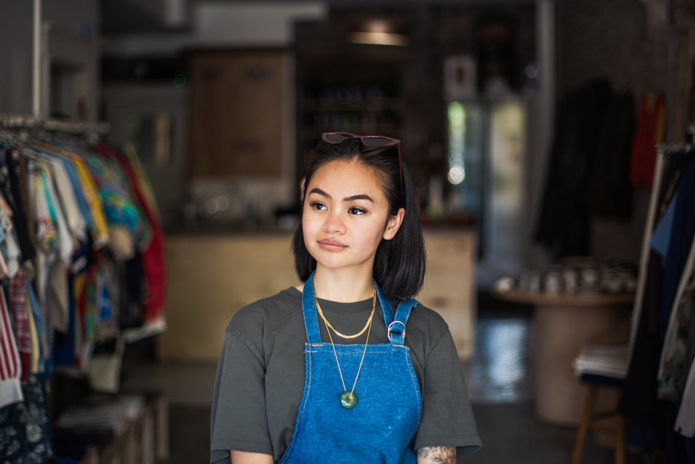 woman stands in store with apron on