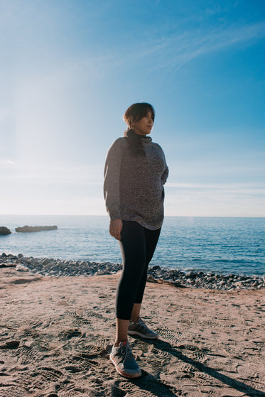 woman stands thoughtful on a beach in the morning sun