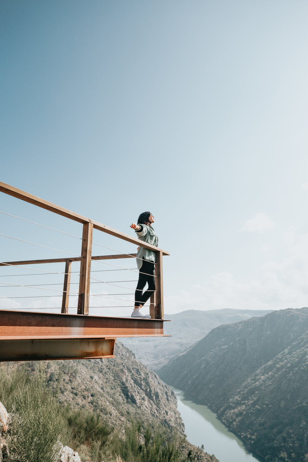 woman stands with arms out surrounded by blue sky