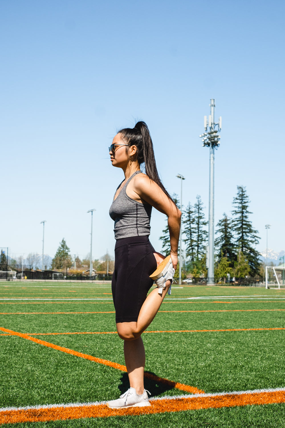 woman stretches her leg while standing on a sport field