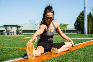 woman stretches on a sports fields grass