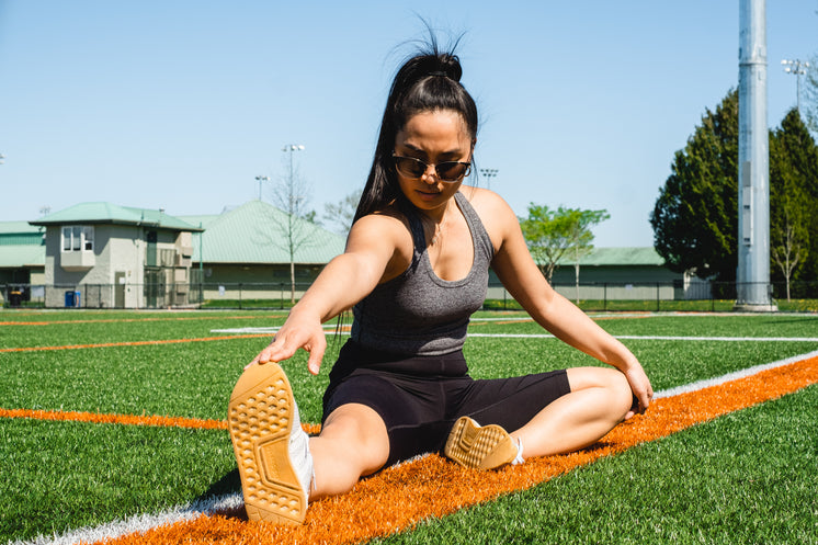 Woman Stretches On A Sports Fields Grass