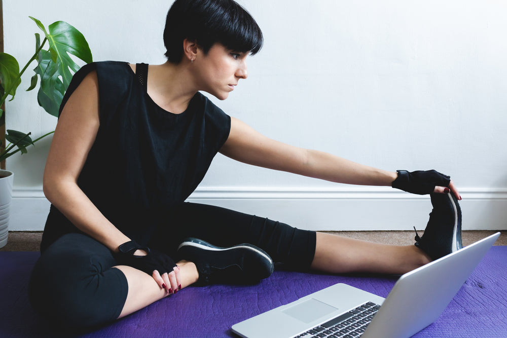 woman stretches while sitting in front of her laptop