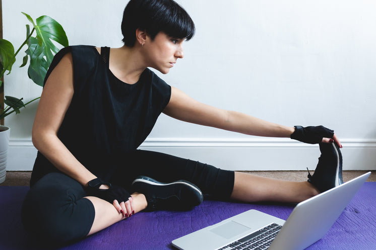 Woman Stretches While Sitting In Front Of Her Laptop