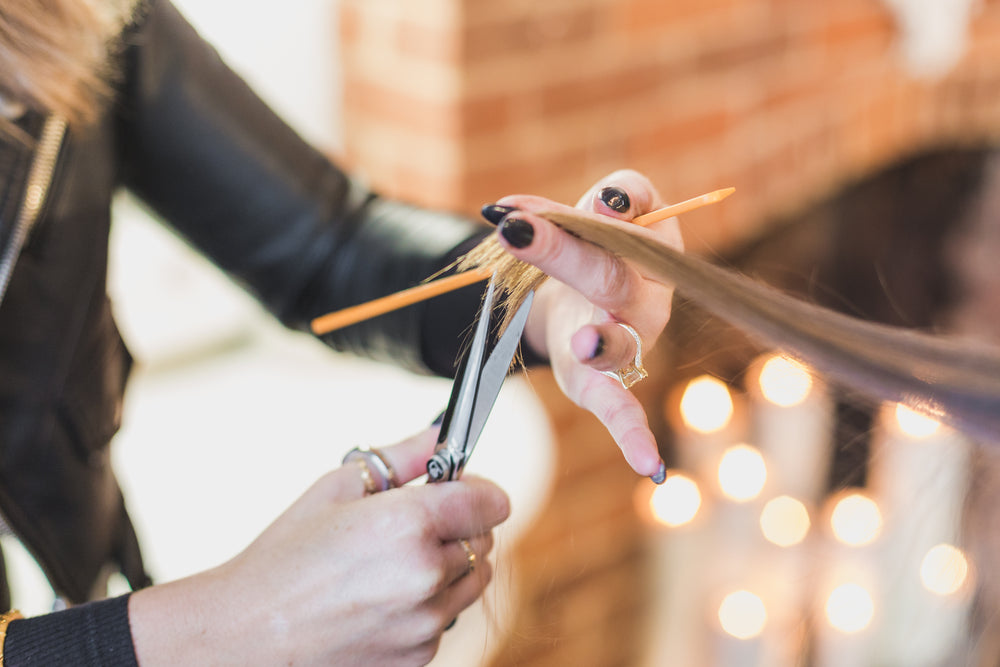 woman stylist cuts hair at salon