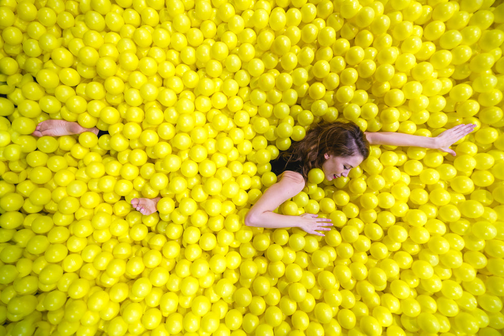 woman swimming through yellow ball pool