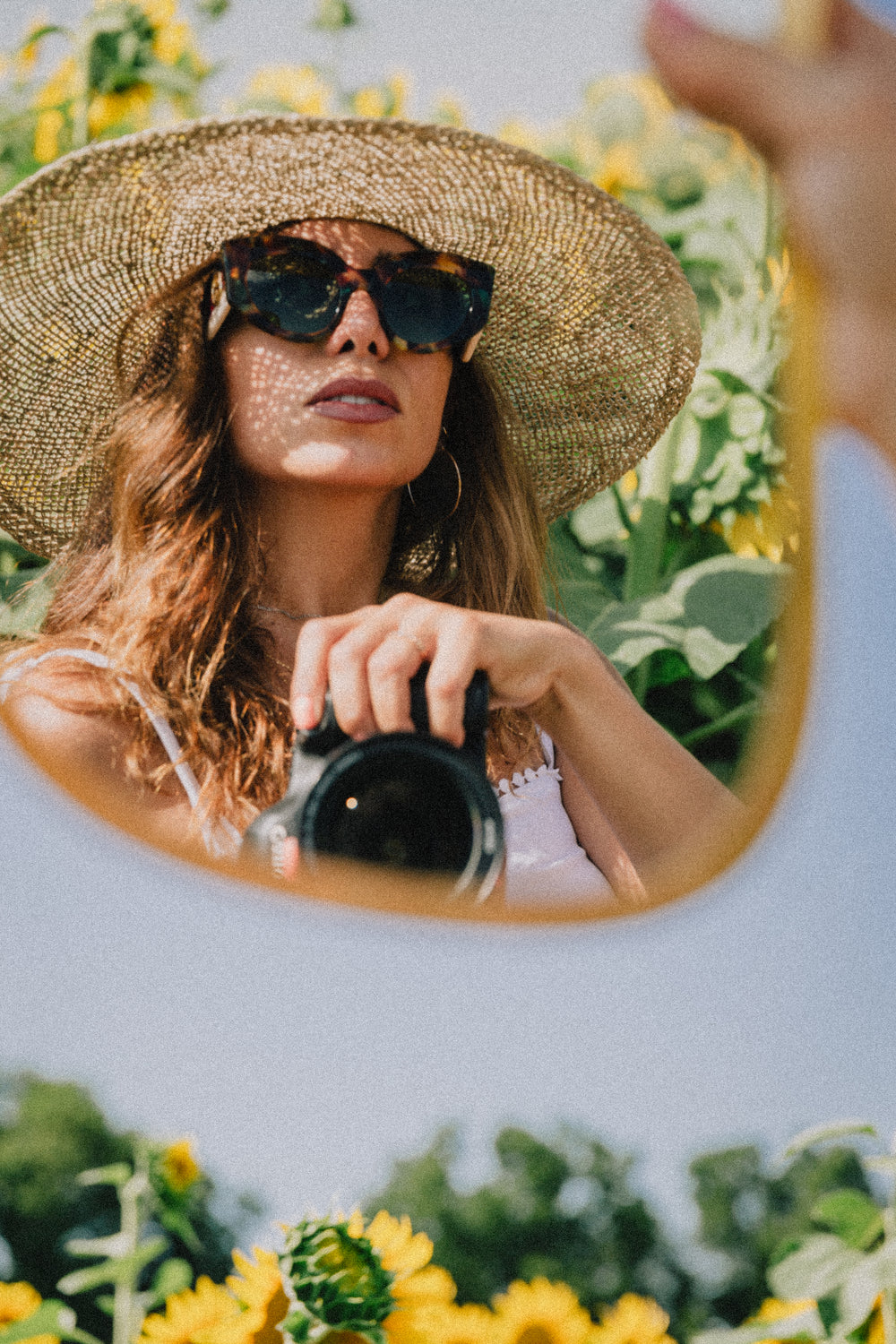 woman takes a mirror self portrait among sunflowers