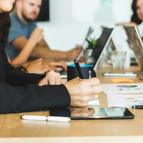 Woman Taking Notes During Team Meeting