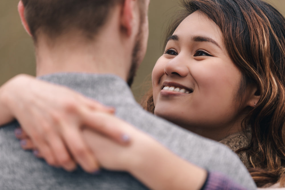 woman throws her arms around a man's neck and smiles