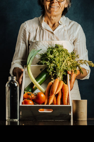 woman tilts a box of vegetables towards the camera